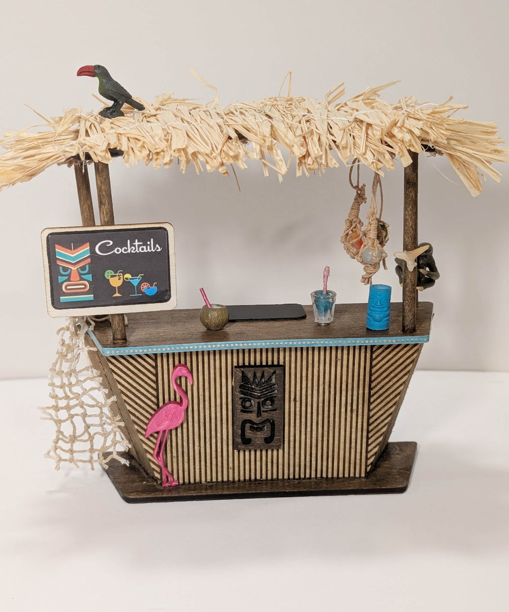 Miniature bar with straw roof, flamingo decor, and cocktails sign on a white background